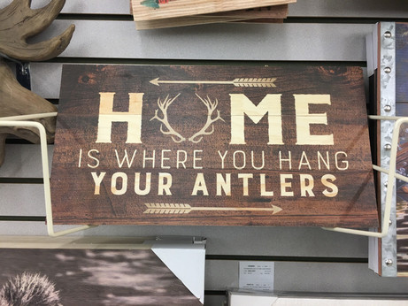 A sign saying “Home is where you hang your antlers”