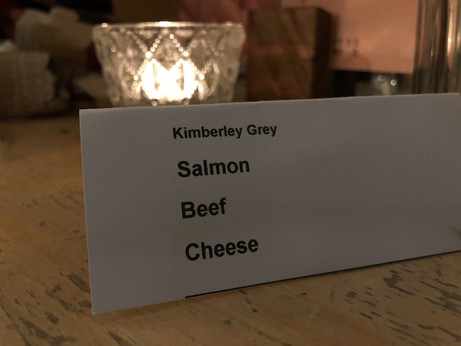 A card with a short list of items on it, reading salmon, beef and cheese. 