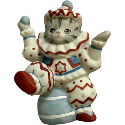 An old-timey cat figurine in a jester outfit sits on her ball and shrugs at the world, staring blankly into the middle distance
