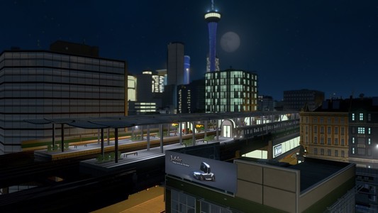 A screenshot from the game Cities: Skylines. It's night time, most of the city dark but for the moon passing by a tall, pointed building. An elevated metro train passes by in the foreground. 