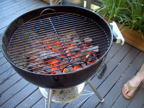 A grill, as in a raised hemispherical metal cooking implement with a metal grille covering a pile of smouldering charcoal
