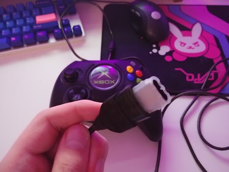 an original xbox controller with the weird plug in the foreground