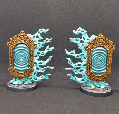 The Umbral Spellportal miniatures from Age of Sigmar. Two paired mirrors with rippled blue-silver surfaces, floating amid blue-green mists