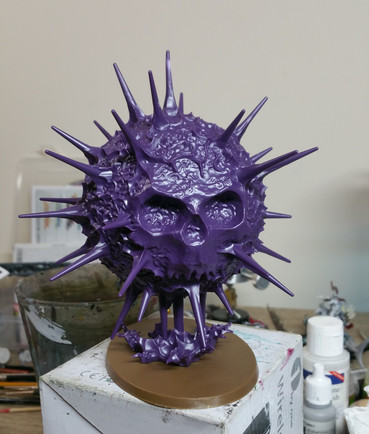 A tabletop miniature of a purple sun, radiating spikes of energy and with a skull face
