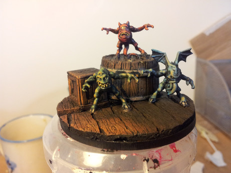 Three miniature demonic familiars perched on dockside scenery