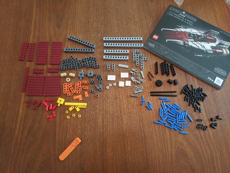 A lot of little tiny LEGO pieces and the instruction booklet for an A-wing from Star Wars. The pieces are moderately carefully knolled.