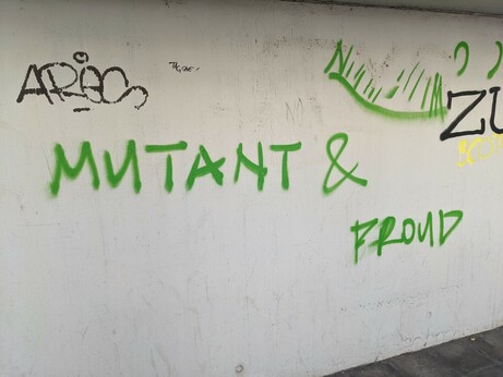 a graffiti that says "mutant & proud"