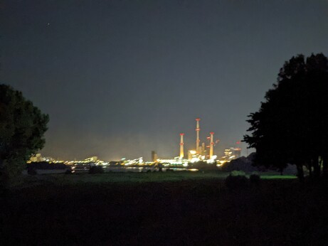 a buch of steelmaking industry buildings at night, brightly lit and a bit blurry