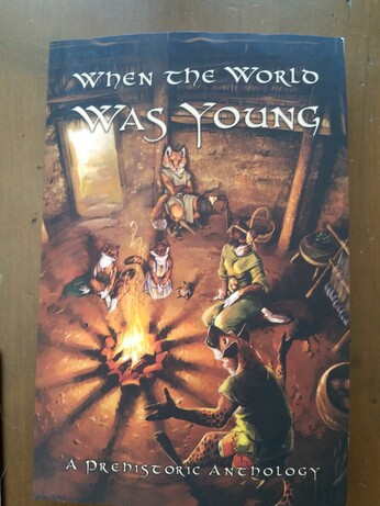 Cover to an anthology seties called When the World Was Young depicting several anthro animals around a fire with a sub heading at the bottom declaring this is A Prehistoric Anthology