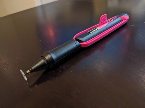 a black pen with a flat plastic tip and a pink headphone jack wrapped around it