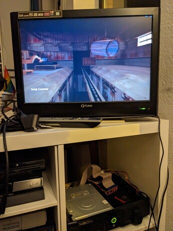 an open Xbox with an SSD lying in the hard drive tray running Half-Life