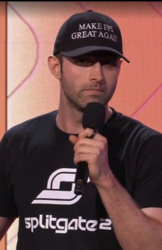 a guy wearing a splitgate 2 shirt and a hat that says "make fps great again"